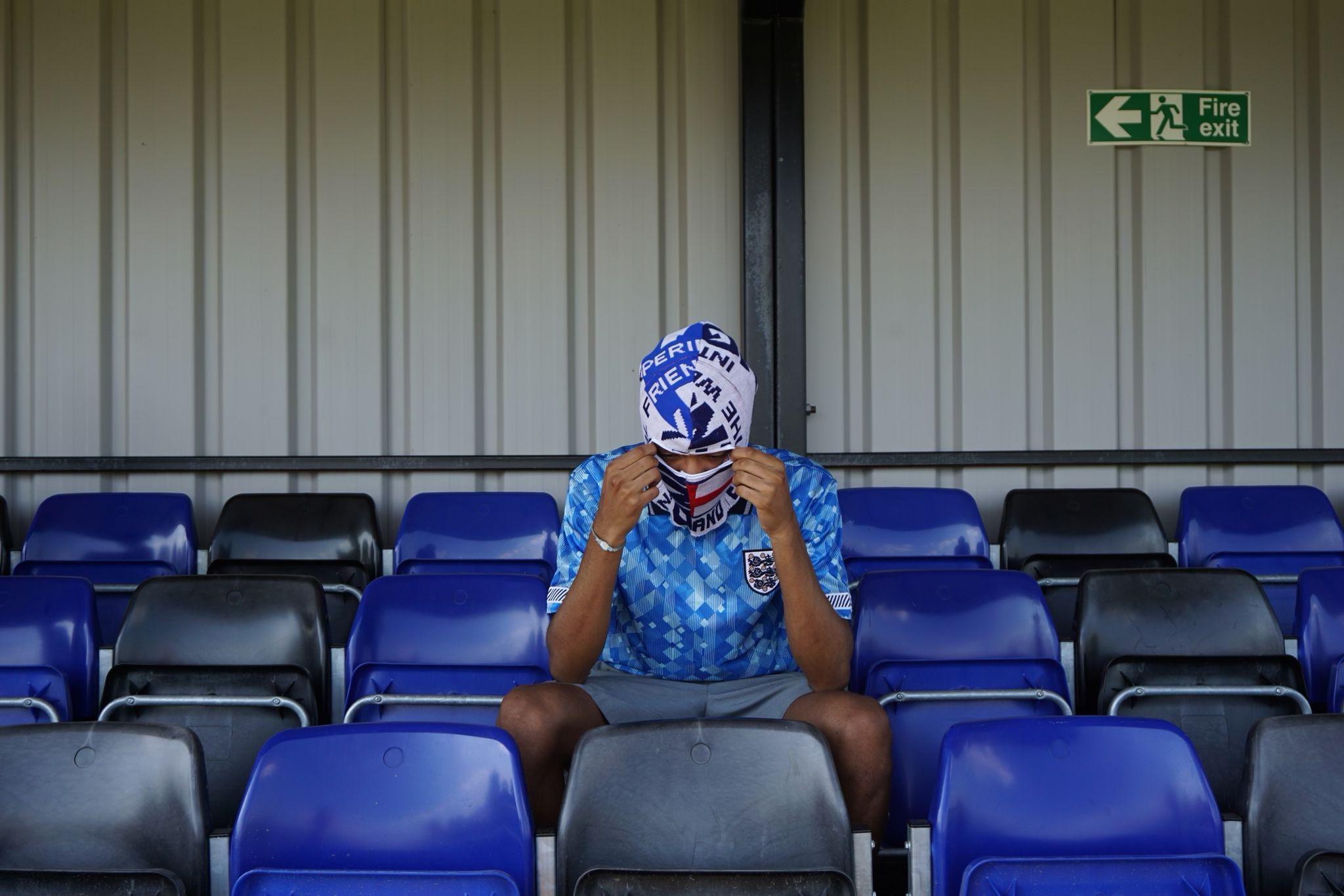 Our model wearing our England football scarf balaclava sitting in the stands at a football ground